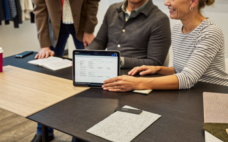 Salesperson explaining a flooring financing payment plan to a couple at a showroom table