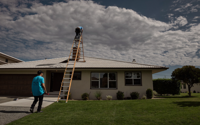 Roofer inspecting storm-damaged tiles while the homeowner watches, handling roofing storm leads fast