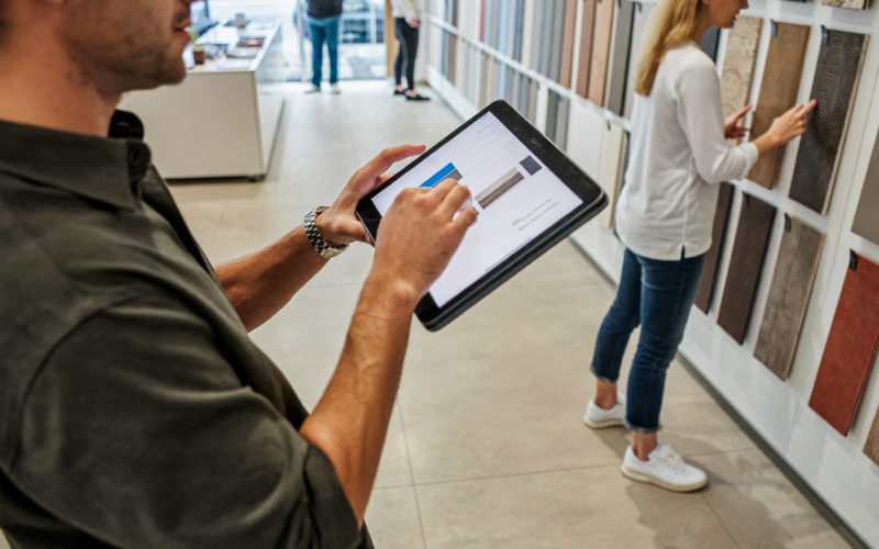 Flooring salesperson using a tablet beside sample boards, practical AI for flooring stores